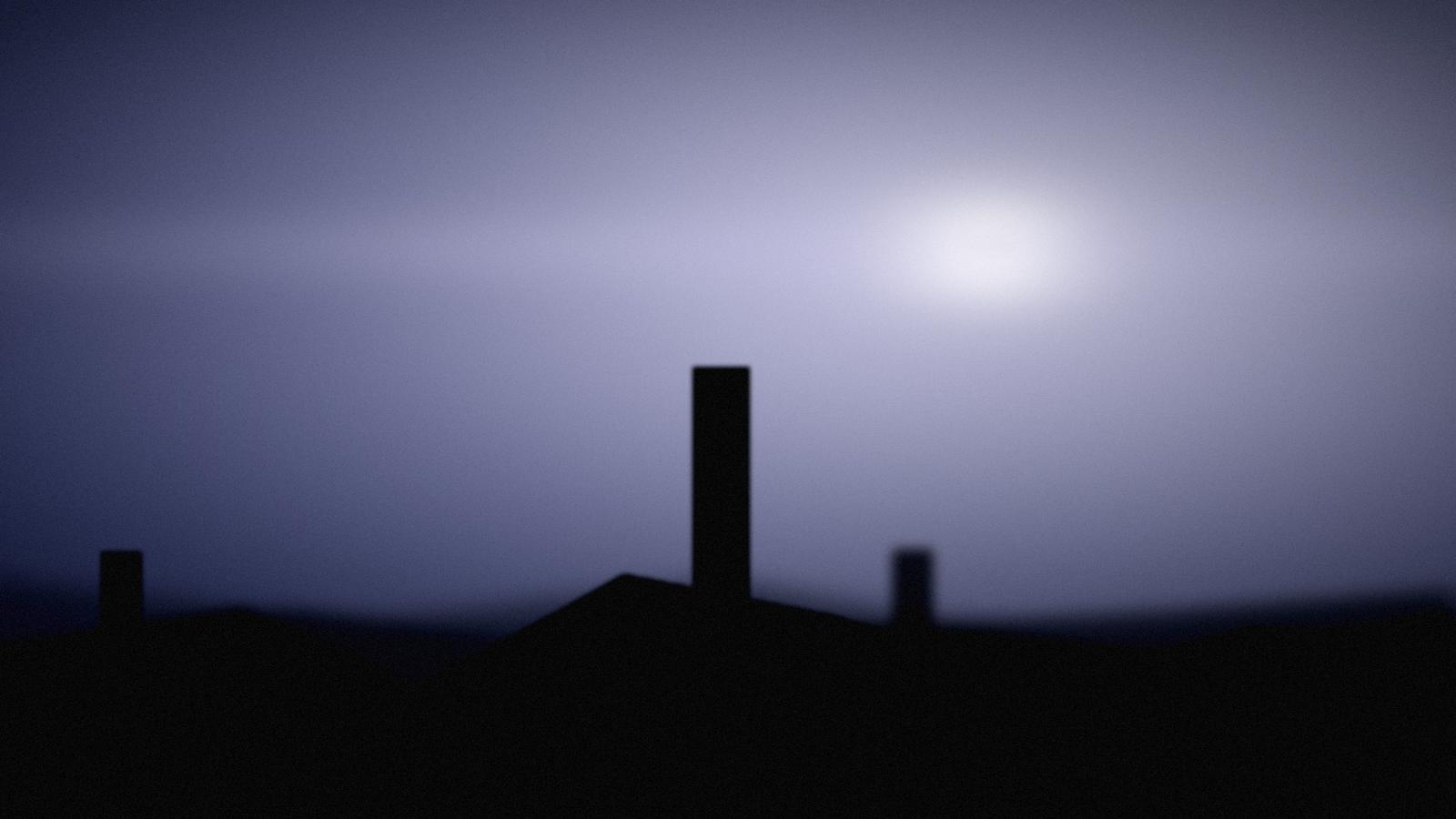 Blue pre-dawn light over a low city skyline.